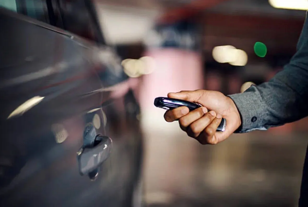 Driver pressing a replacement key fob to unlock a car in a parking garage
