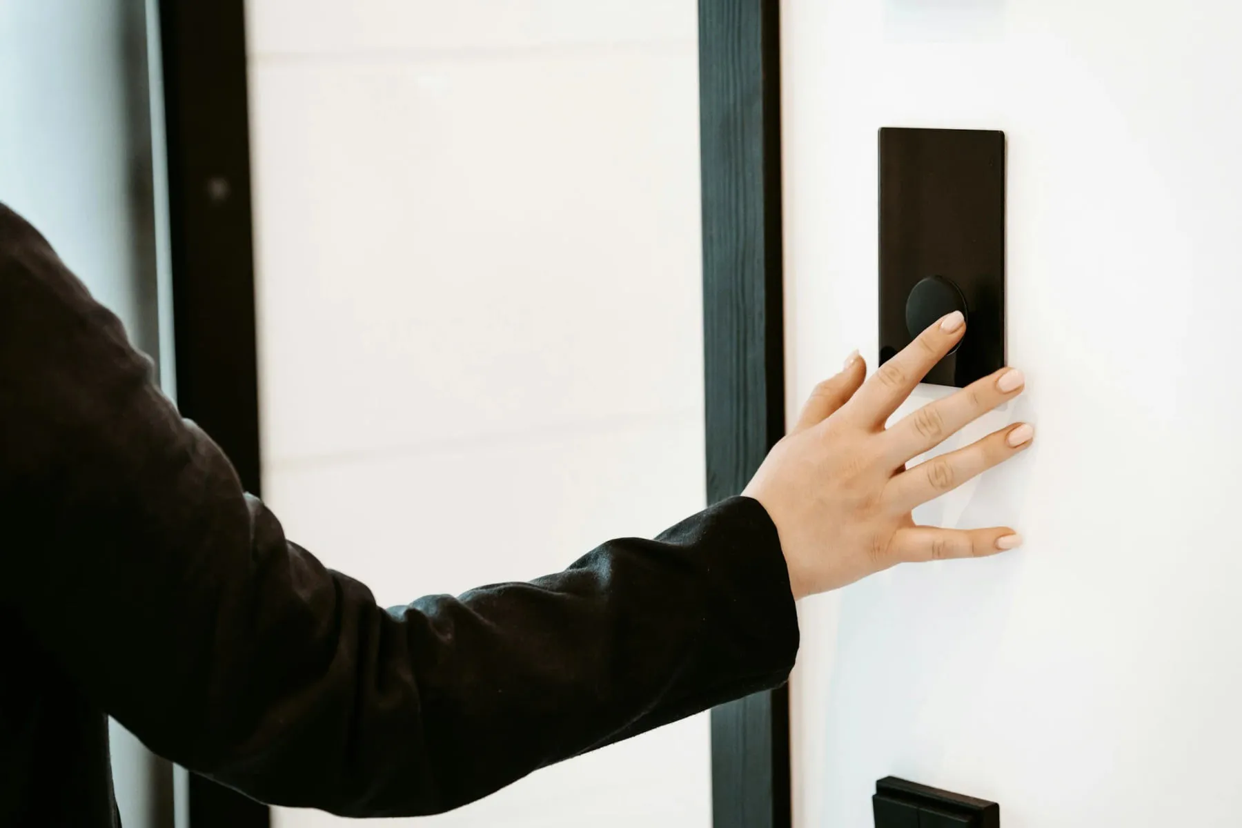 Hand pressing a keyless entry keypad mounted beside a commercial glass door